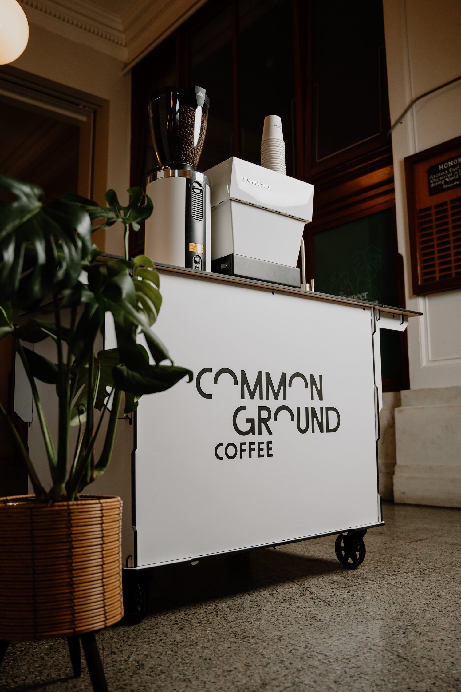 Common Ground Coffee white mobile cart with La Marzocco espresso machine in an event lobby